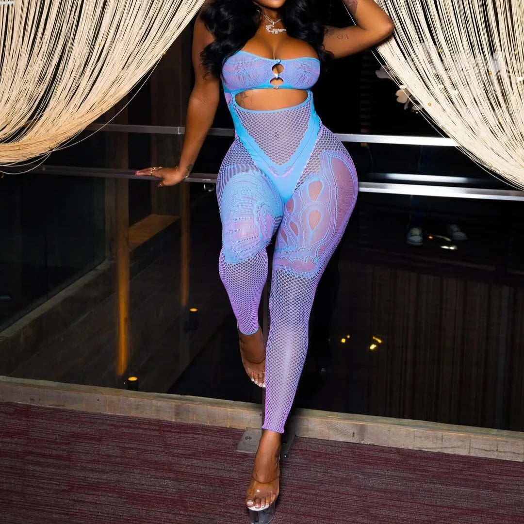 Person wearing a blue fishnet outfit standing in a room with curtains.